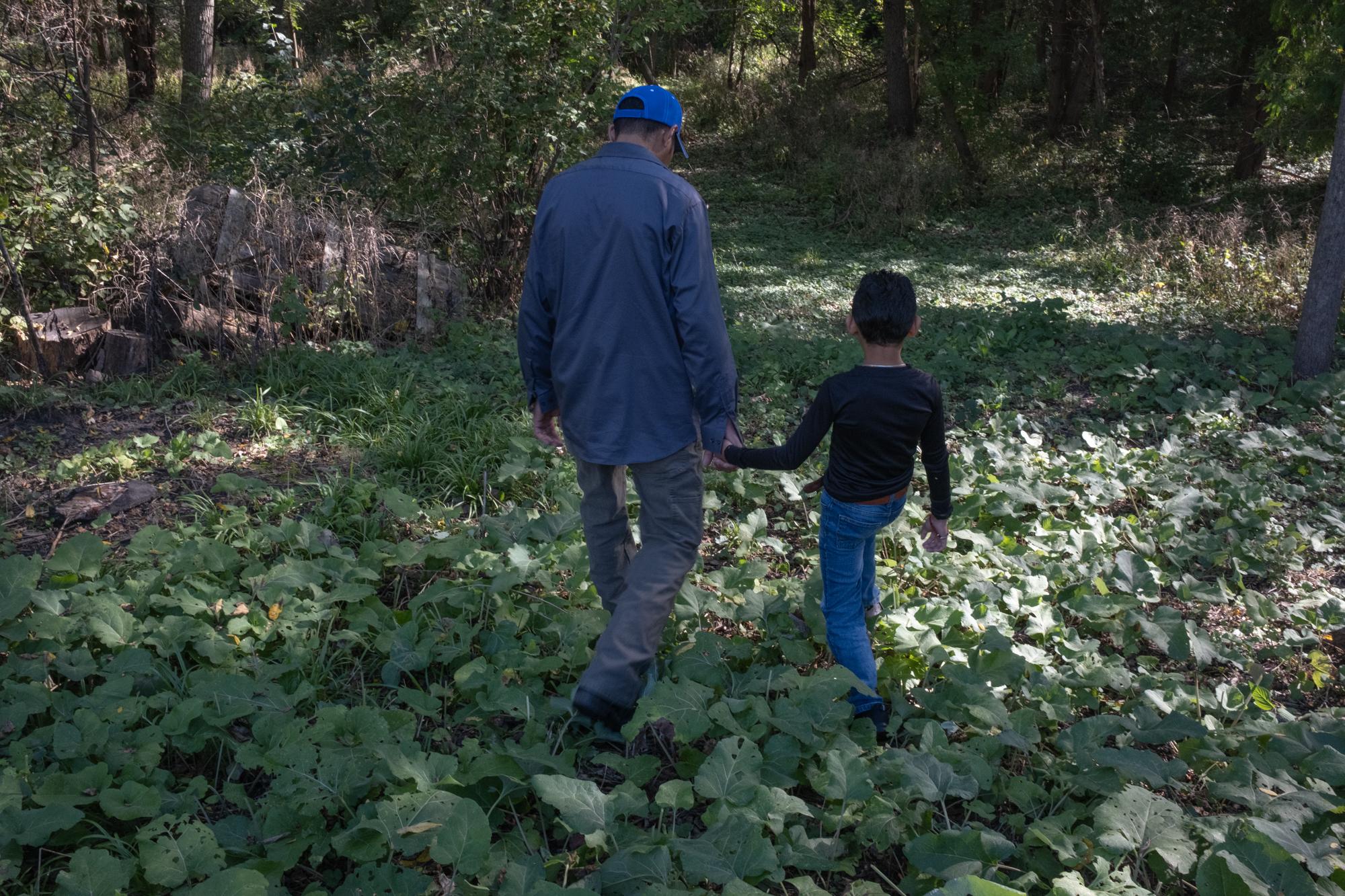 ProPublica - Immigration  - Ariel and his son Sander walk down to the woods next to...