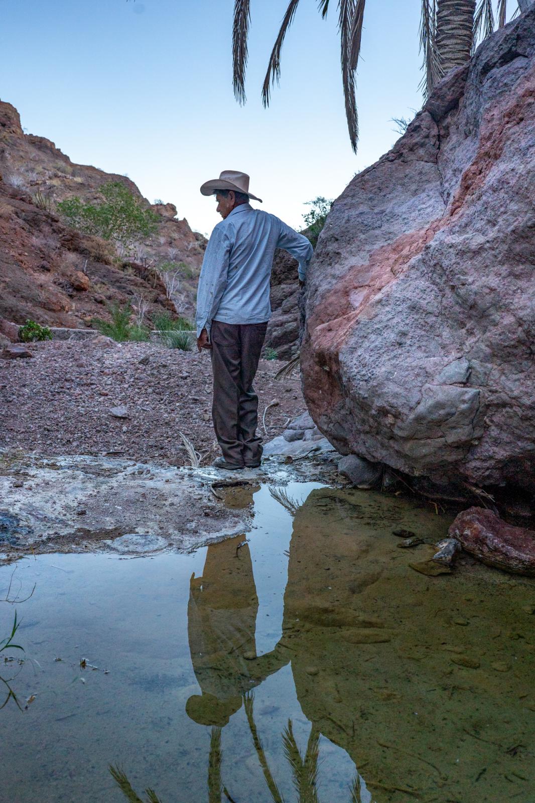 Until We Are Gone  - Alejo Romero stands next to a water hole close to his...