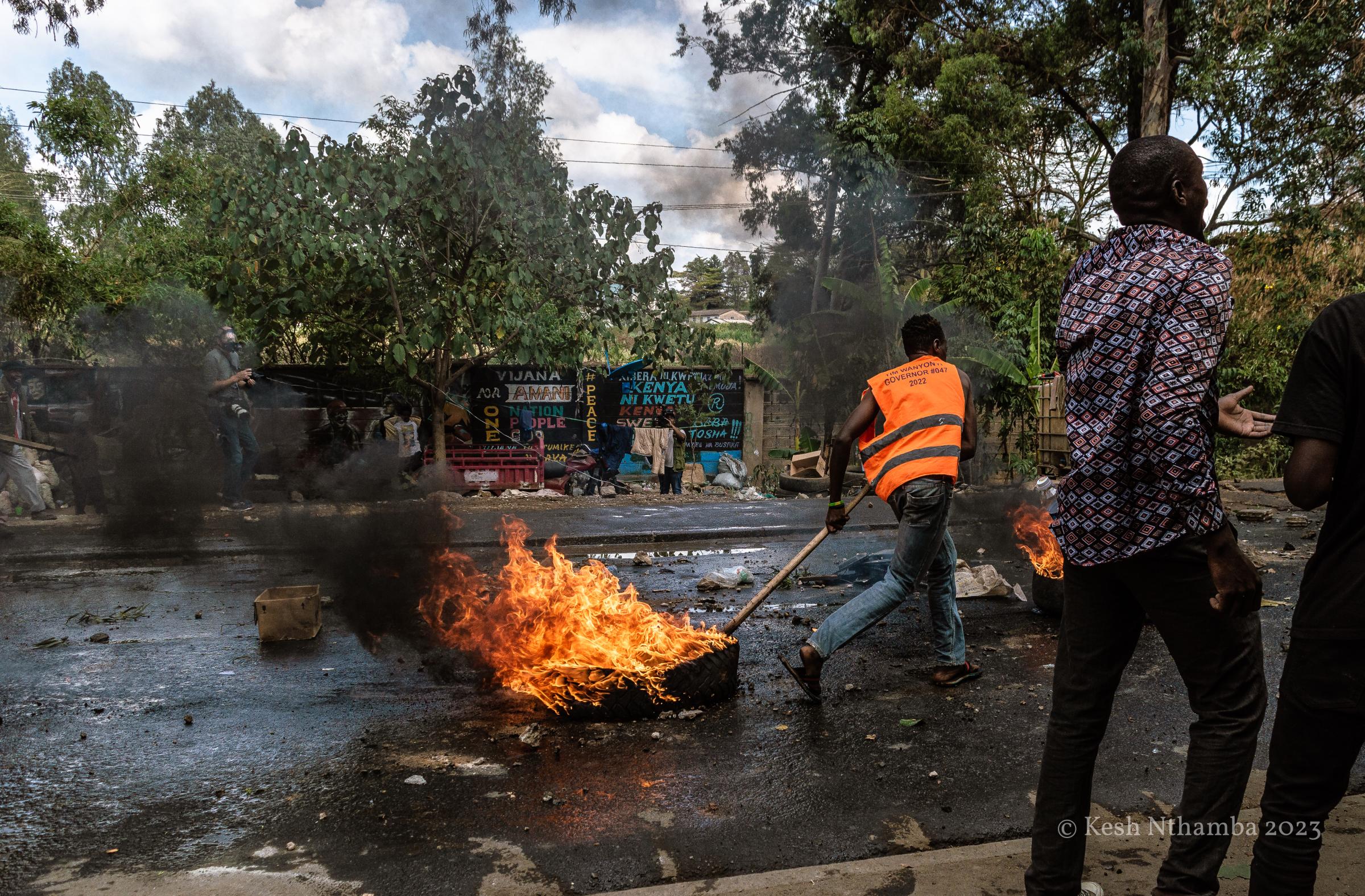 Anti-government Kibera Protests - A protestor drags a burning tyre during the...