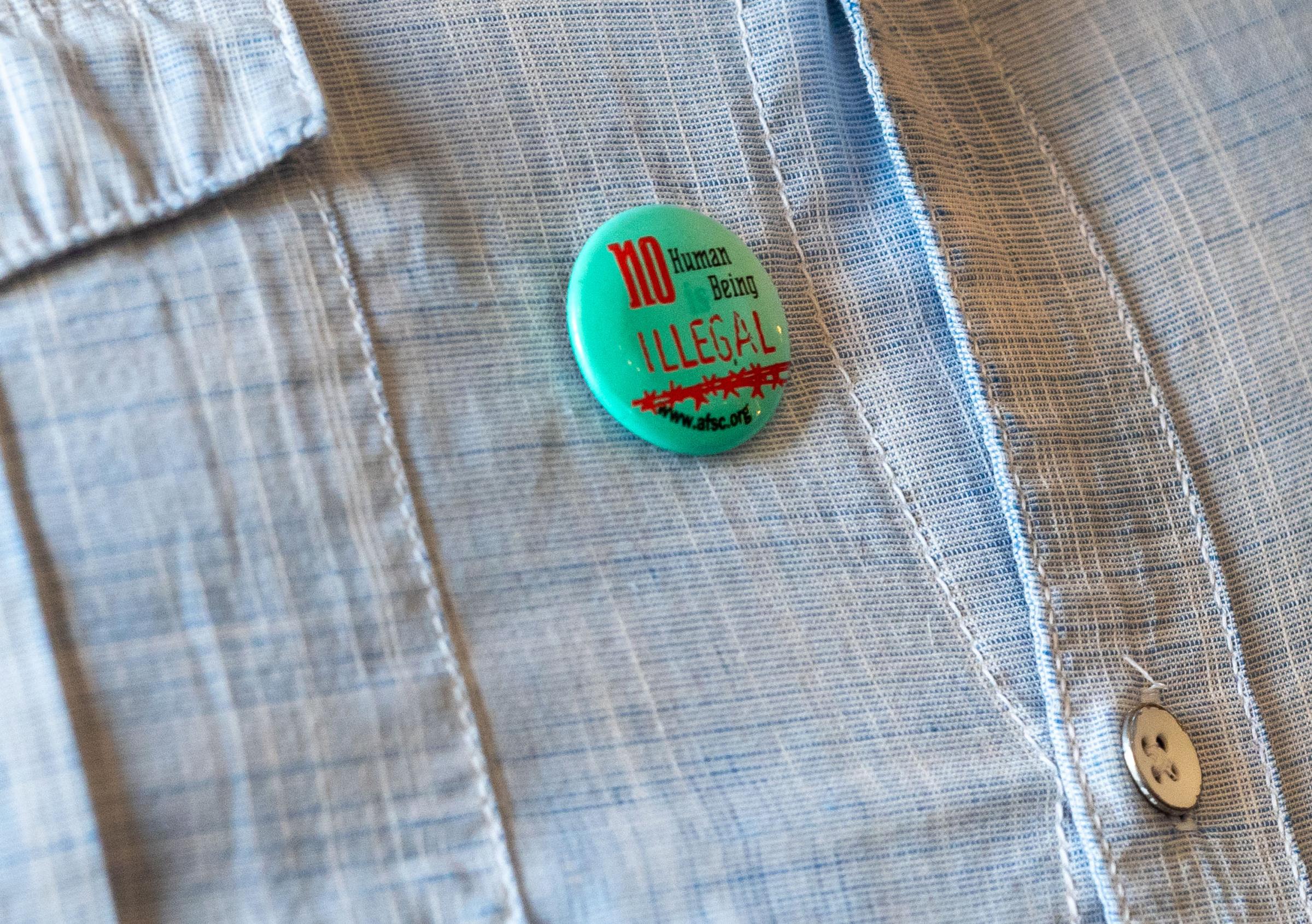 Lack of Translation Services for the Latino Community - Luis Magaña wears a pin that reads ‘No Human Being...