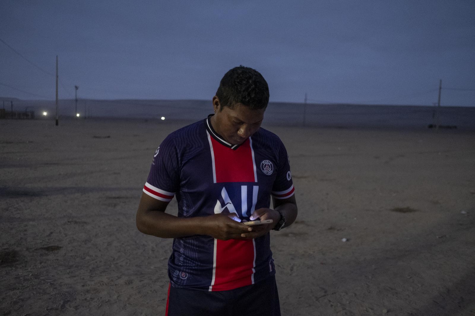 Migration Border - Manuel rosales sostiene su celular en búsqueda de...