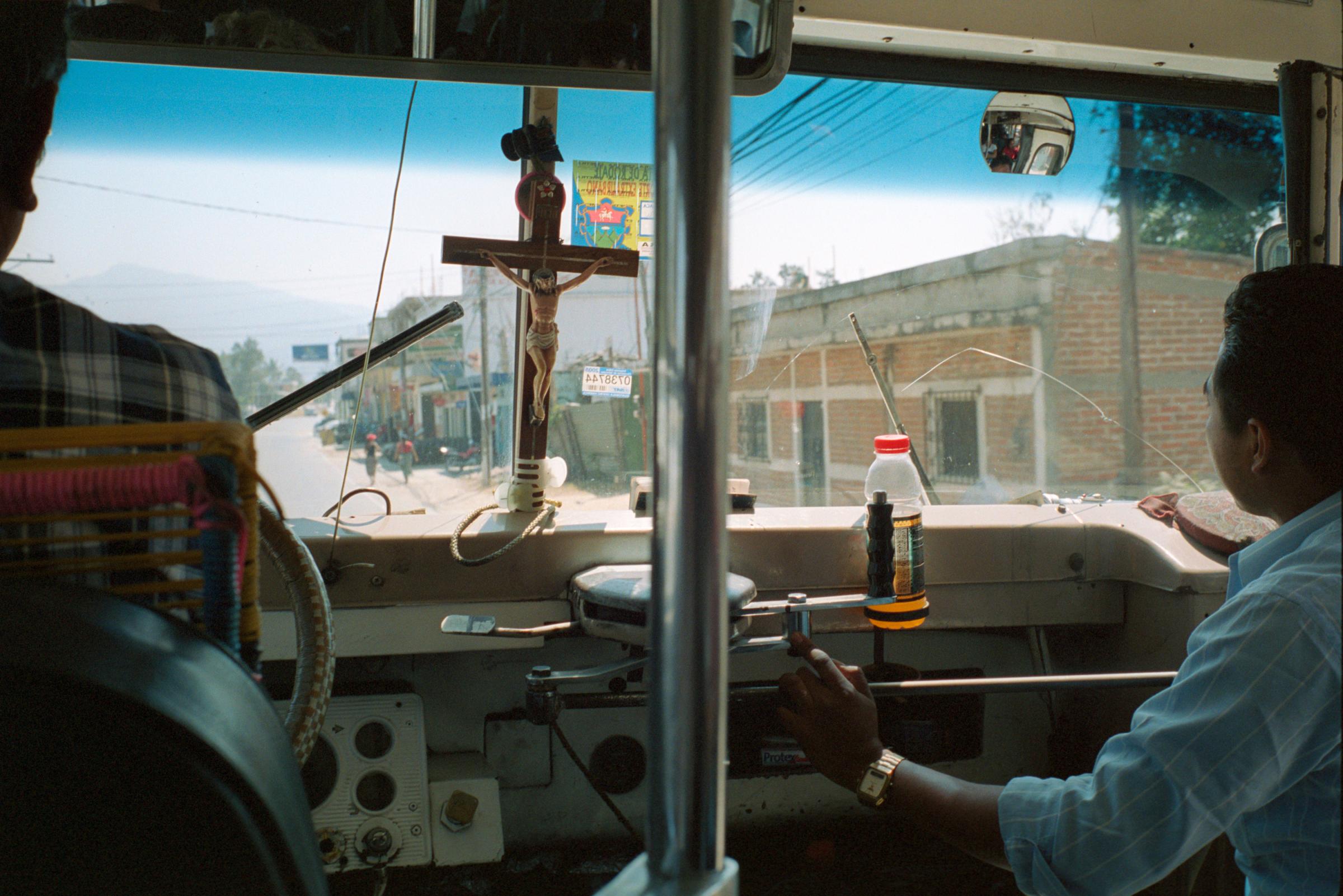 With God and Ayudante Across Guatemala - A crucifix decorates the windshield of a bus in...