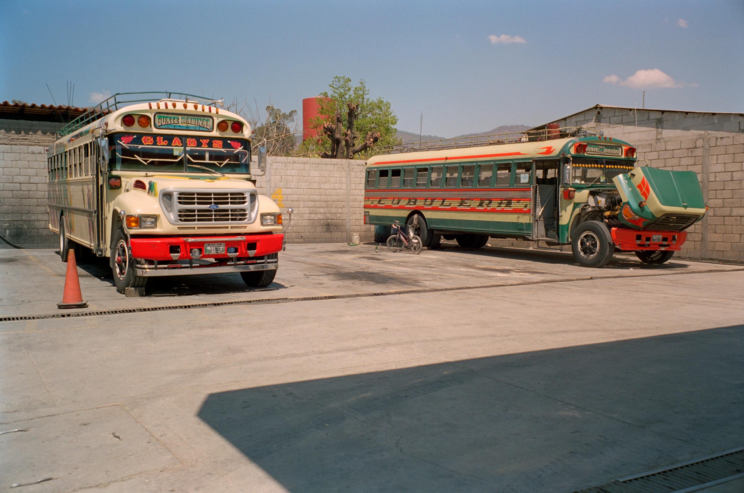 With God and Ayudante Across Guatemala - Two buses waiting to be repaired at the bus station of...