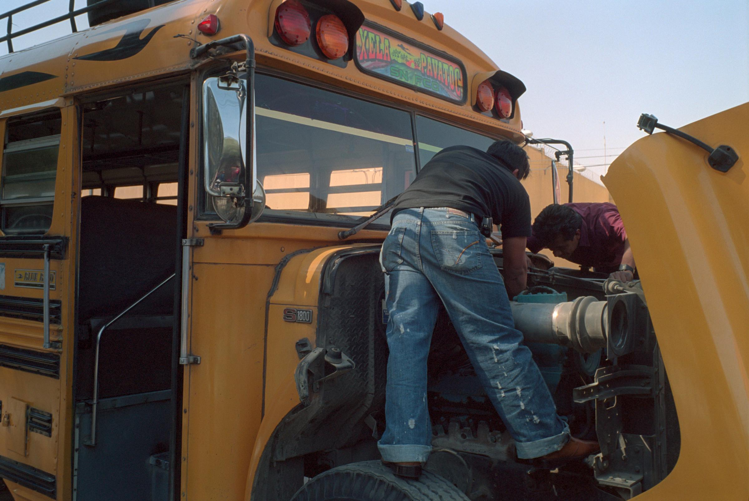 With God and Ayudante Across Guatemala - Two men repair the motor of a Chicken Bus....