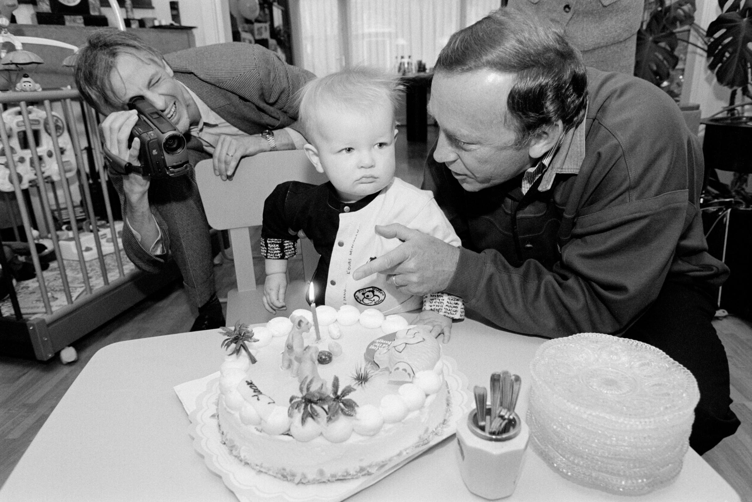 A boy&#39;s first birthday. His father makes a video while his uncle tries go get him to blow out the candle on a Lion King cake. Amstelveen,...