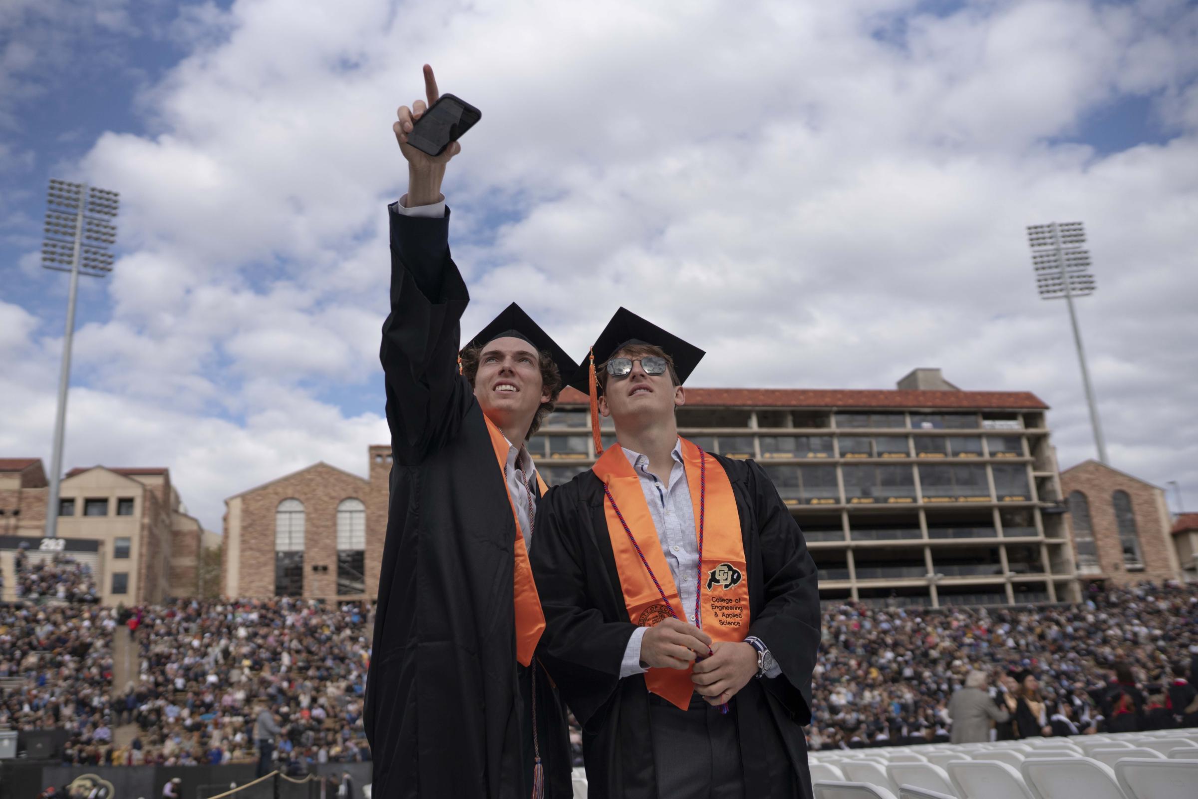 CU Boulder Commencement  - A couple of graduates point out to where their families...