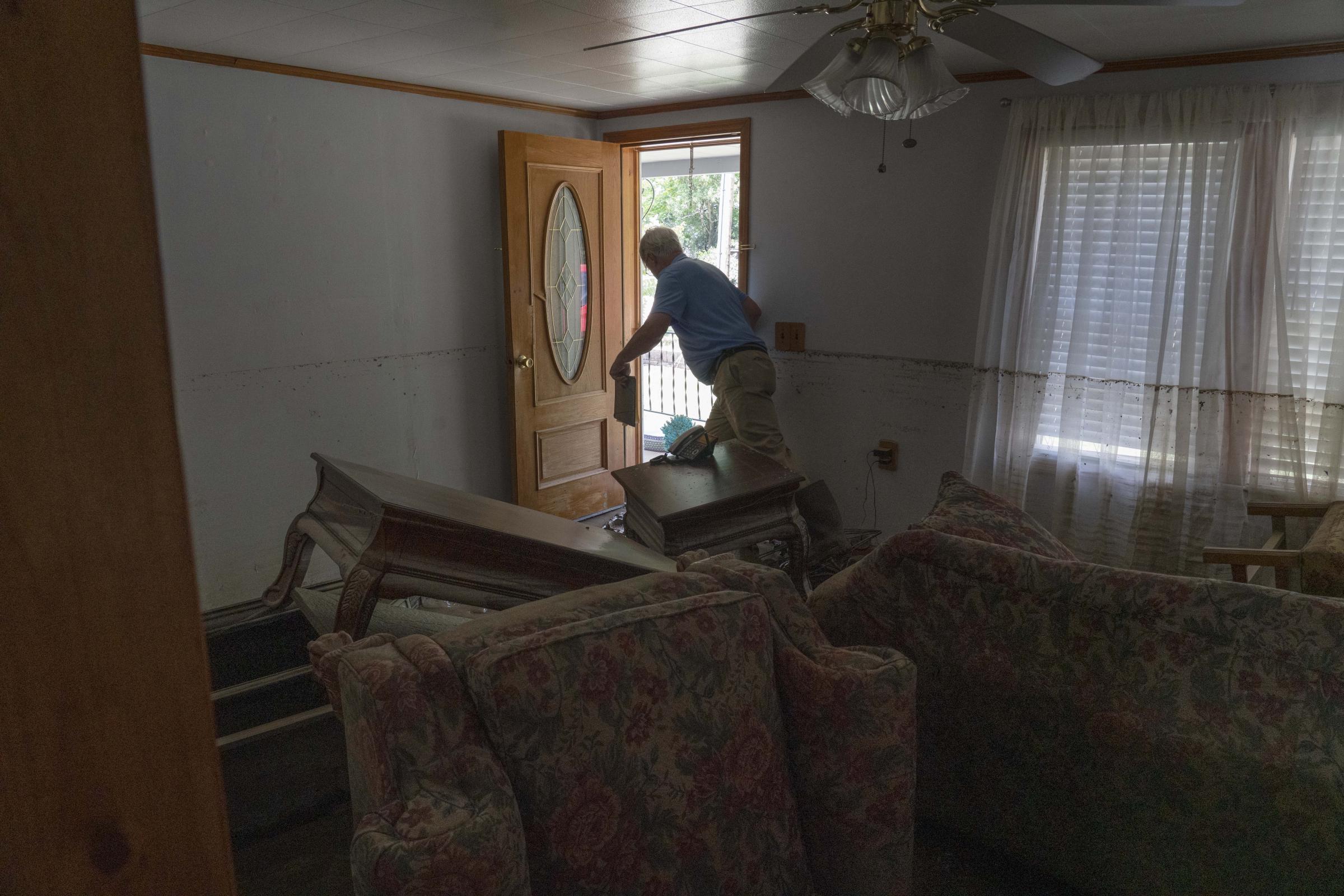 Flooding In Appalachia - A volunteer trudges through a living room that was...