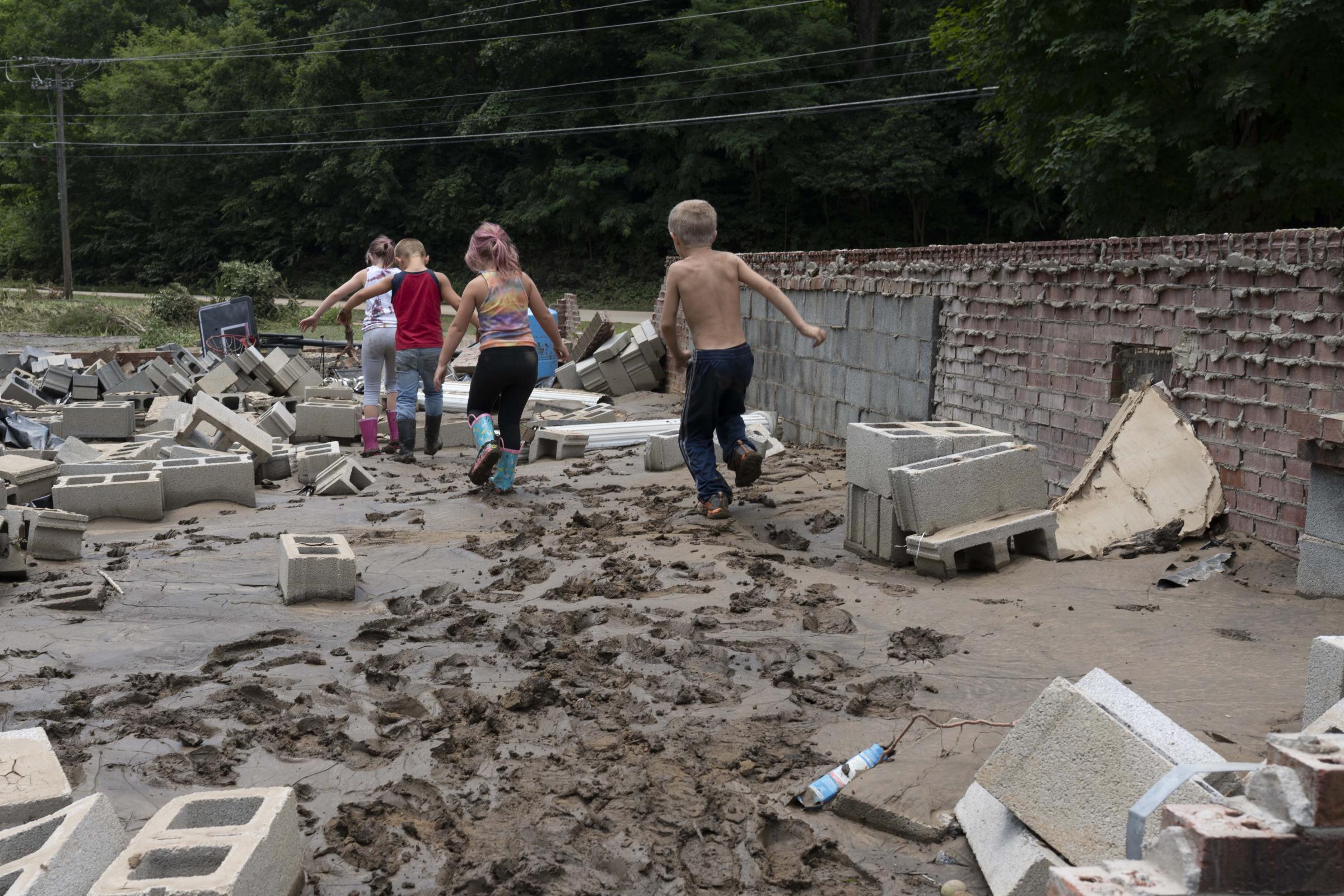 Flooding In Appalachia - Children play in the damaged foundation of a home after...