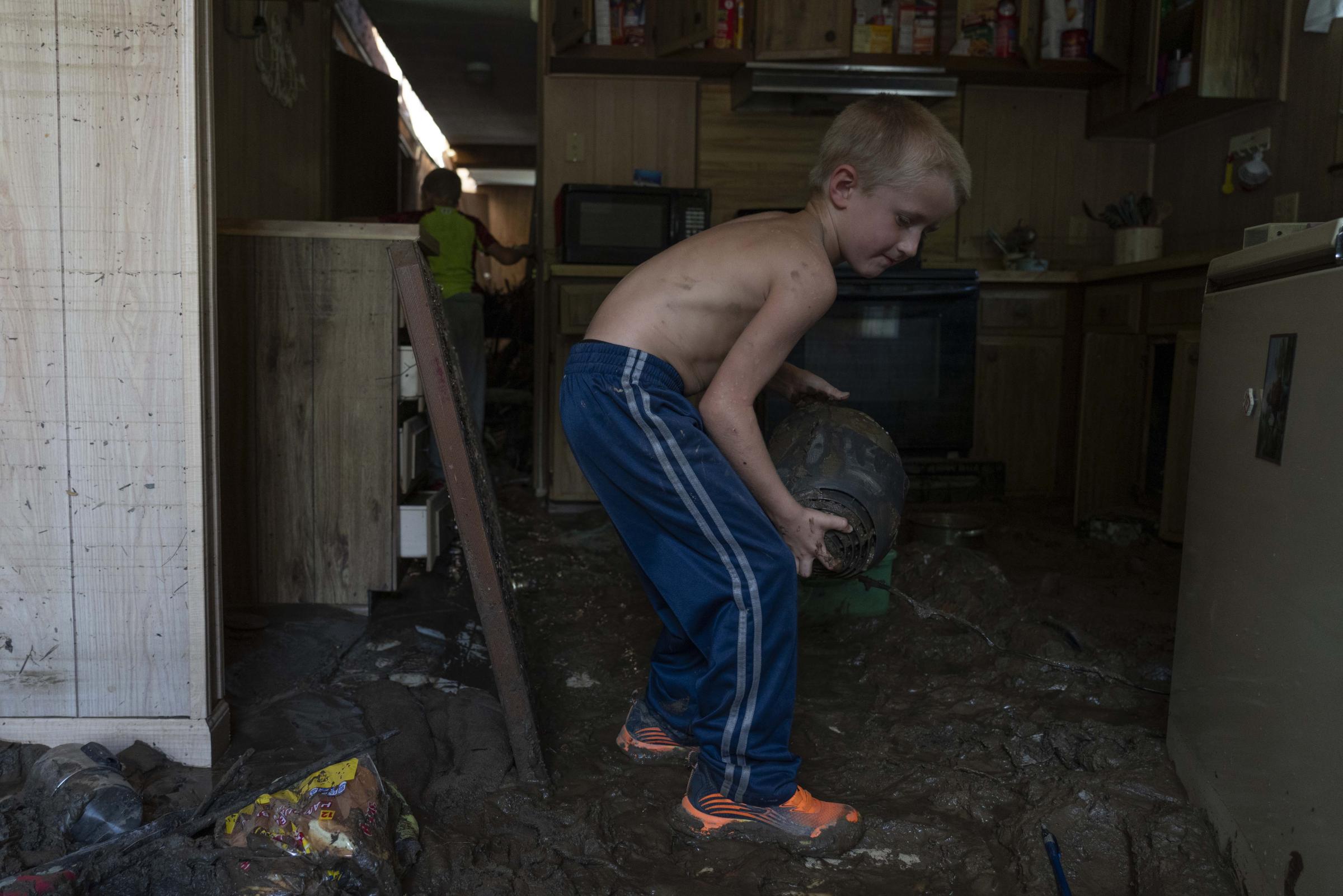 Flooding In Appalachia - Colton Mosley, 6, picks up salvaged materials in his...