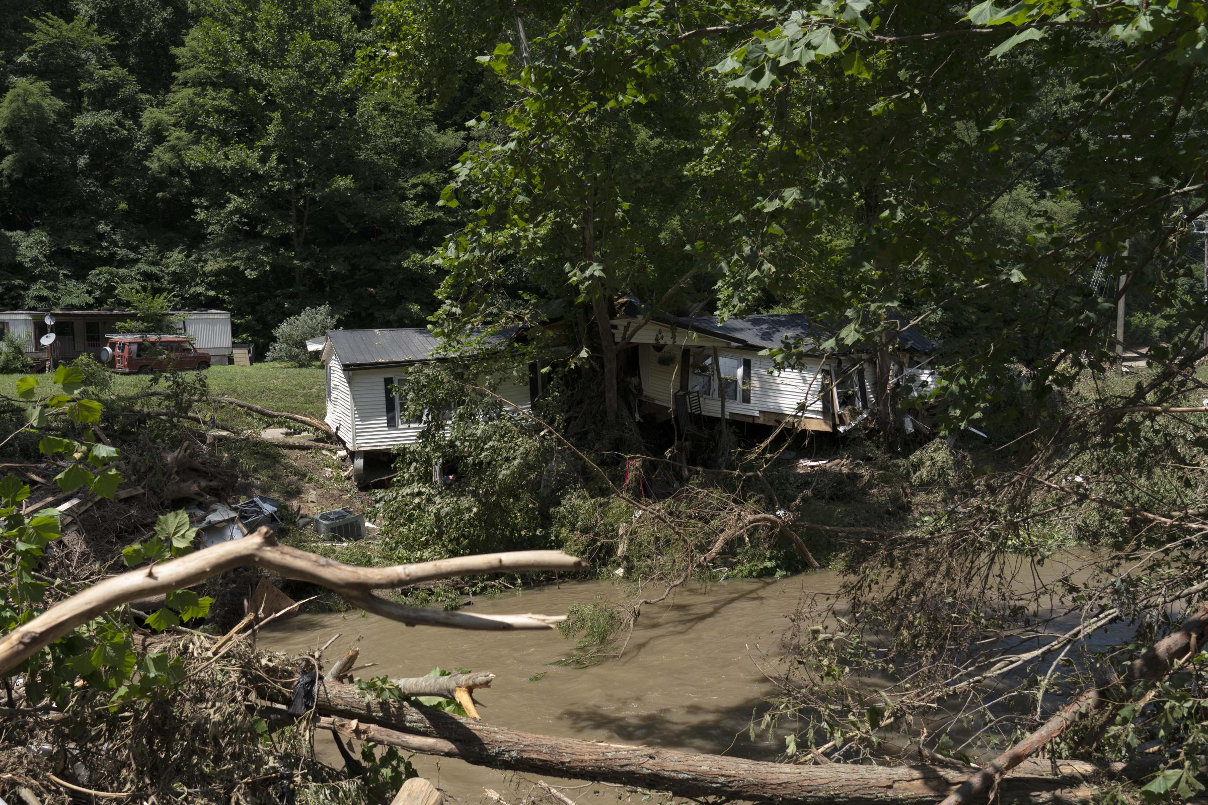 Flooding In Appalachia - A house sits horseshoed around a tree after torrential...