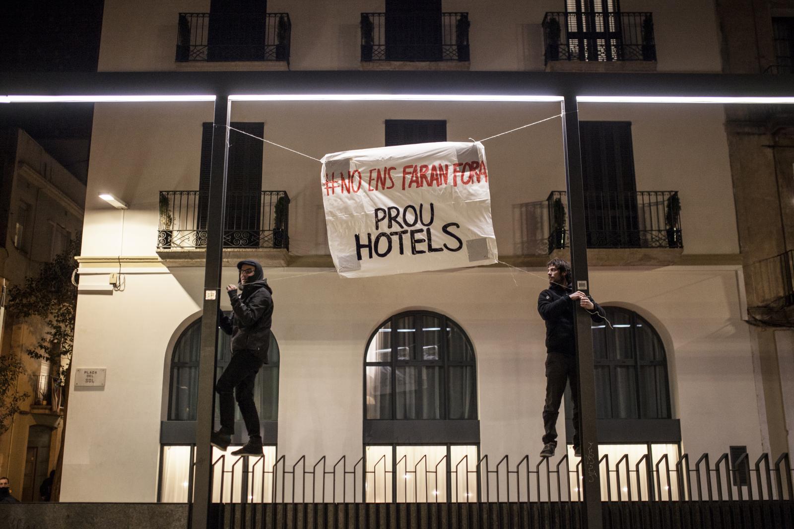Contramotus - Two activists hang up a banner against hotels during a...