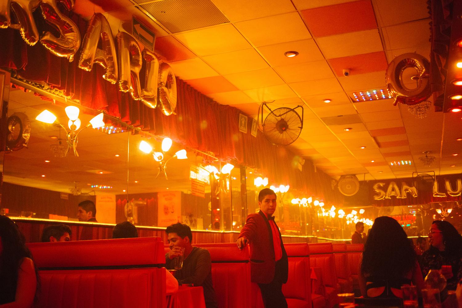 A waiter watches customers arrive at Salón San Luis, a dancehall featuring a live band, in Mexico City, Mexico. 