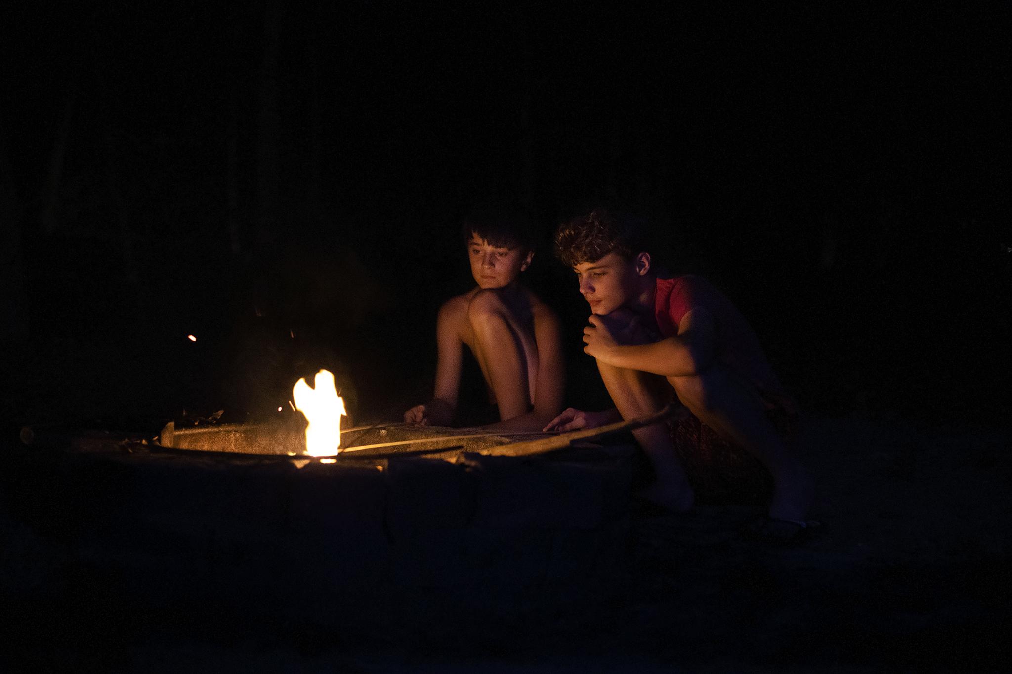 Growing Up - Two friends tend to the campfire they started during a...