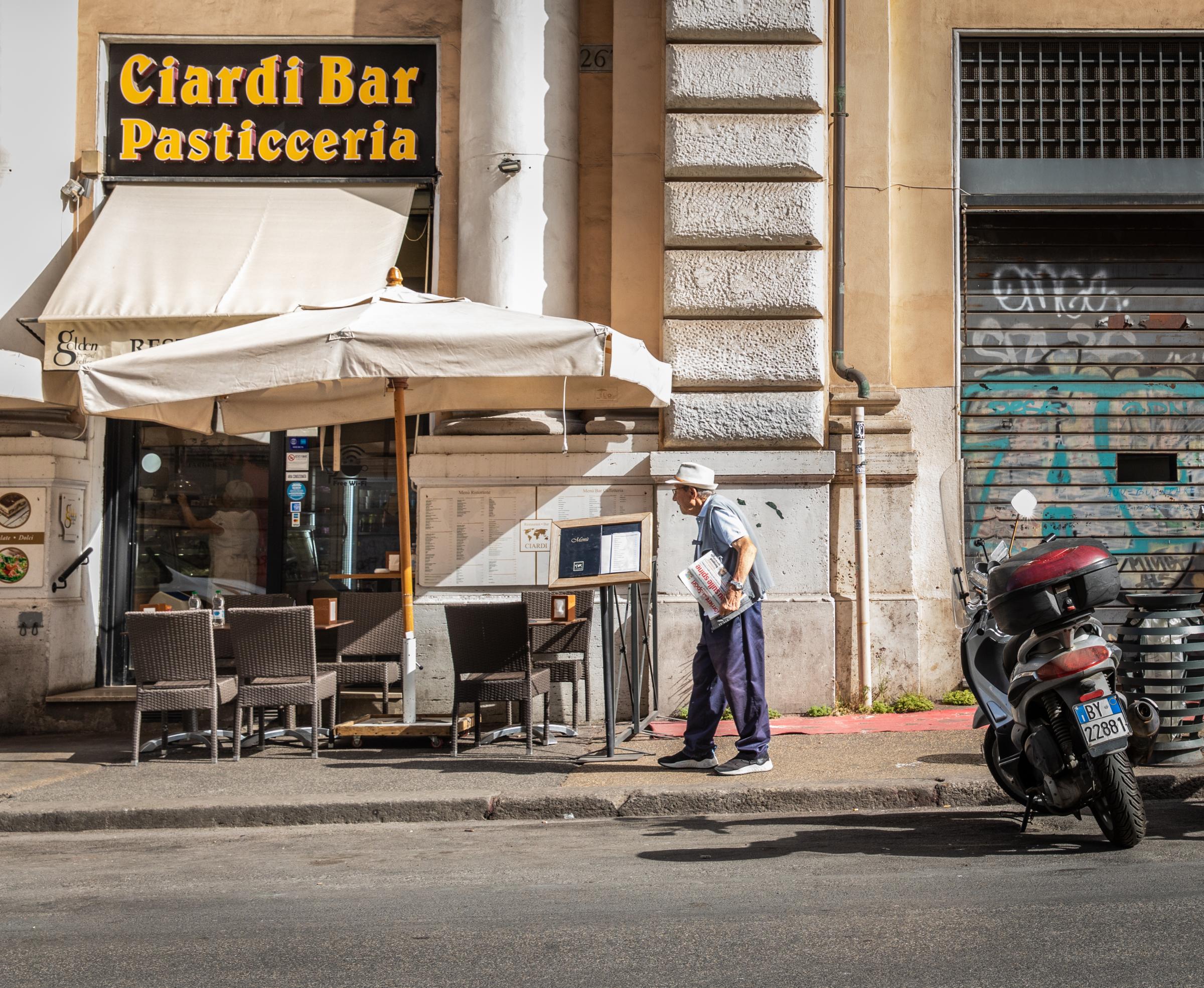 That Bad Boy Rome - A First-timer's Perspective - A man slowly walks to the Ciardi Bar Pasticceria with his newspaper.