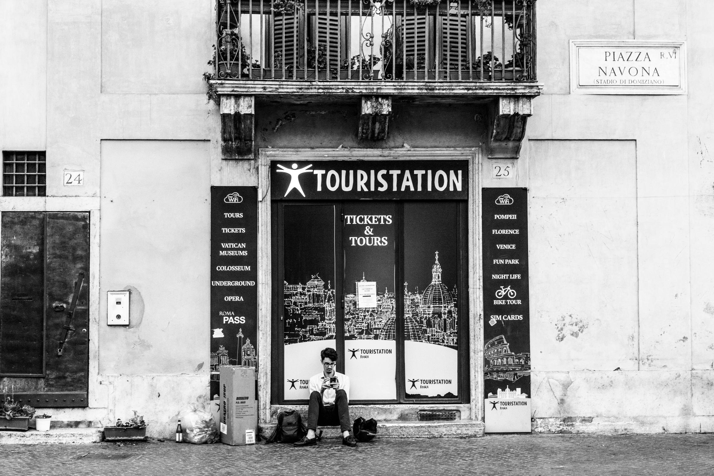 That Bad Boy Rome - A First-timer's Perspective - A man sits outside a closed tourist shop in Rome.