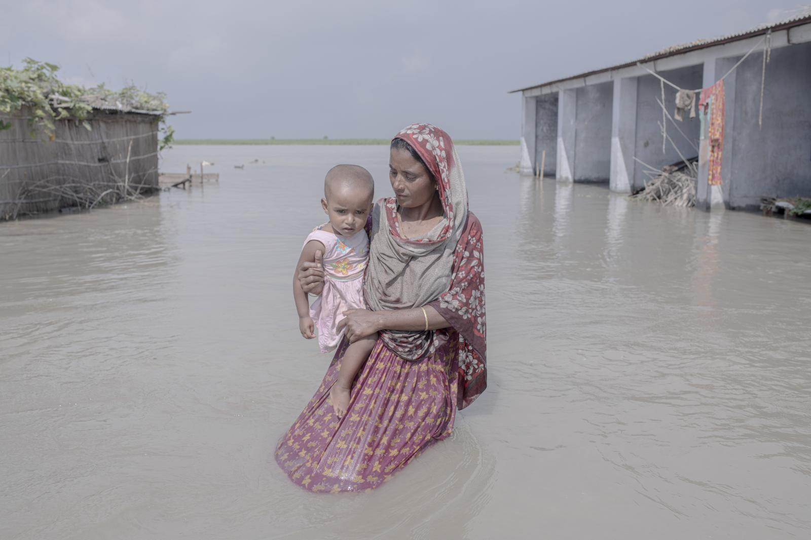 Julekha Begum carries her child through a flooded street.
