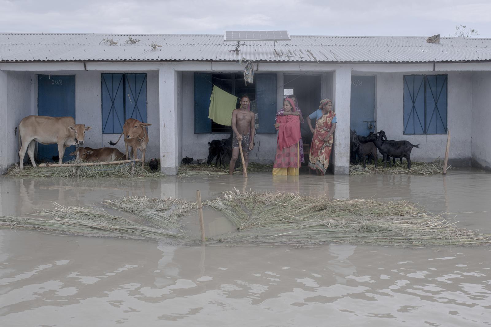 A family stands outside their flooded house.
