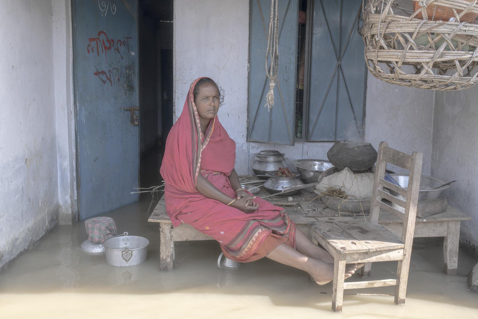 Anu Begum is cooking front of her flooded house.