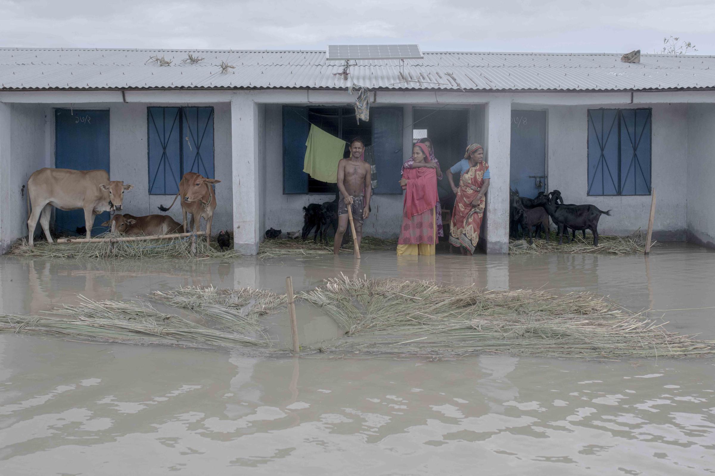 Flood Survival People -  A family stands outside their flooded house. 