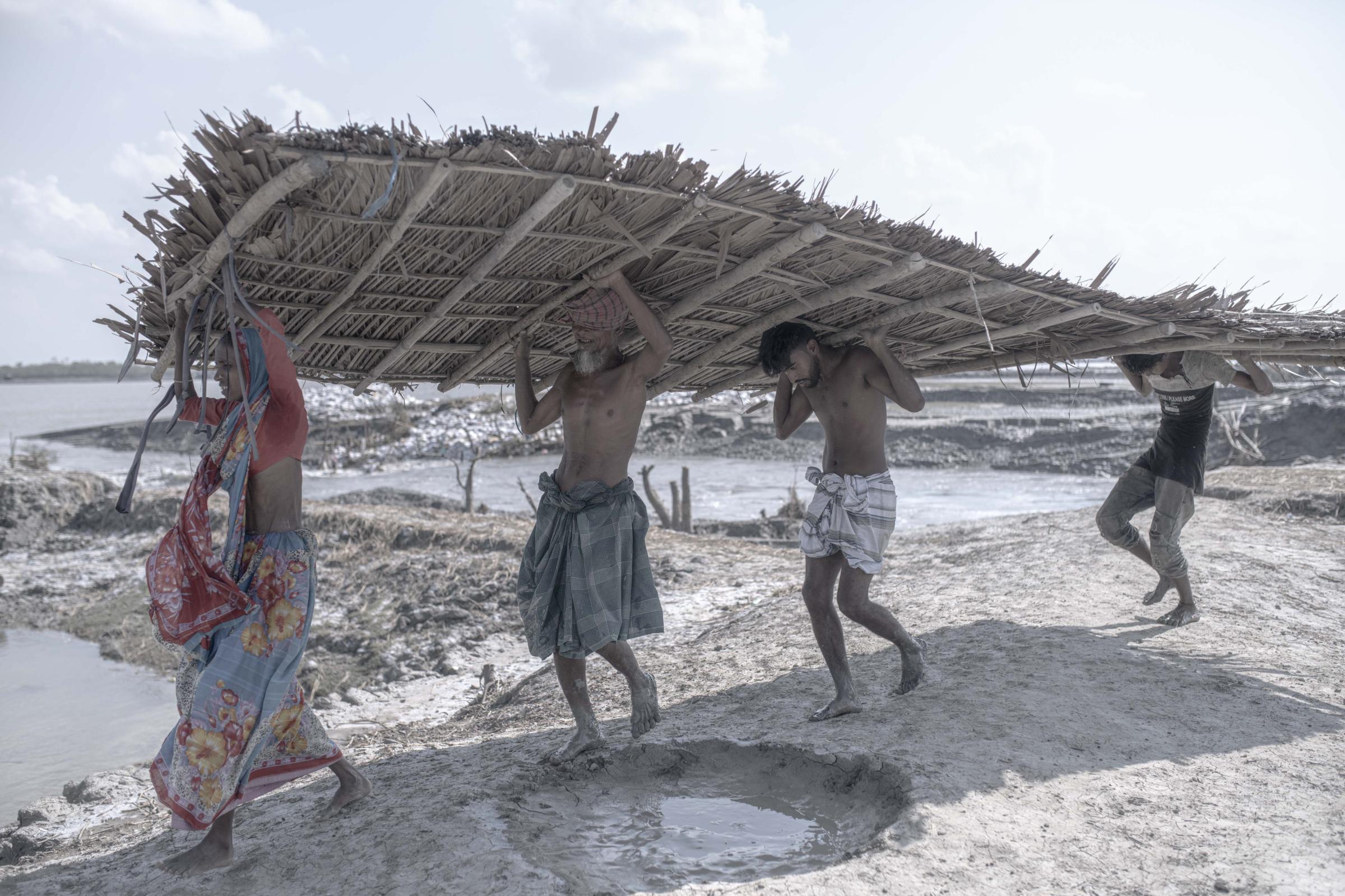 Salt Water's Roar -  Coastal area people carrying a roof of their temporary...