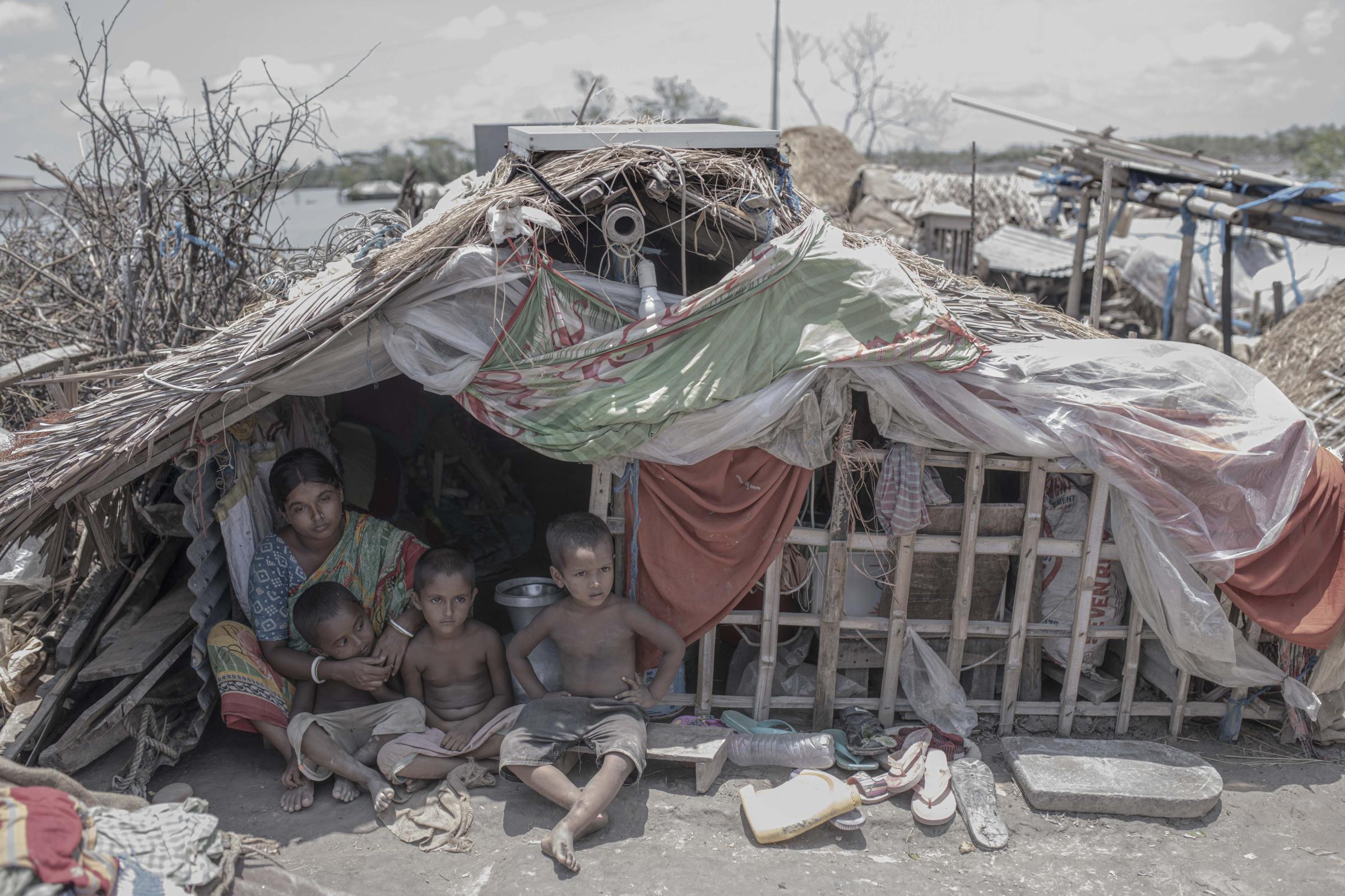 Salt Water's Roar -  A mother with her kids sits in front of her temporary...