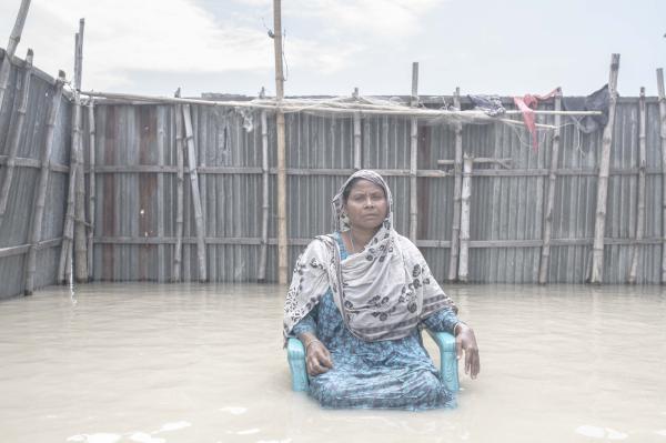Image from Flood Survival People -  Shefali Begum sits in front of their flooded house. 