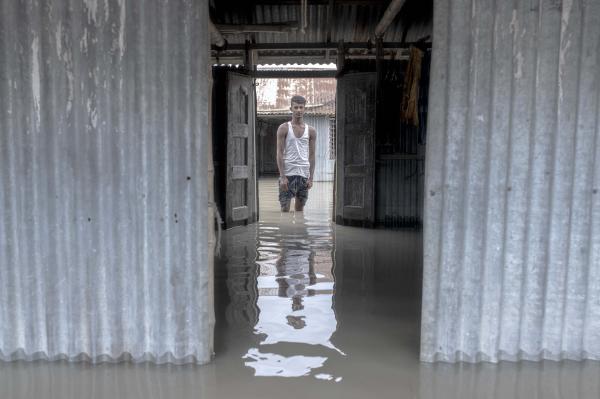 Image from Flood Survival People -  Akbor stands outside his flooded house. 