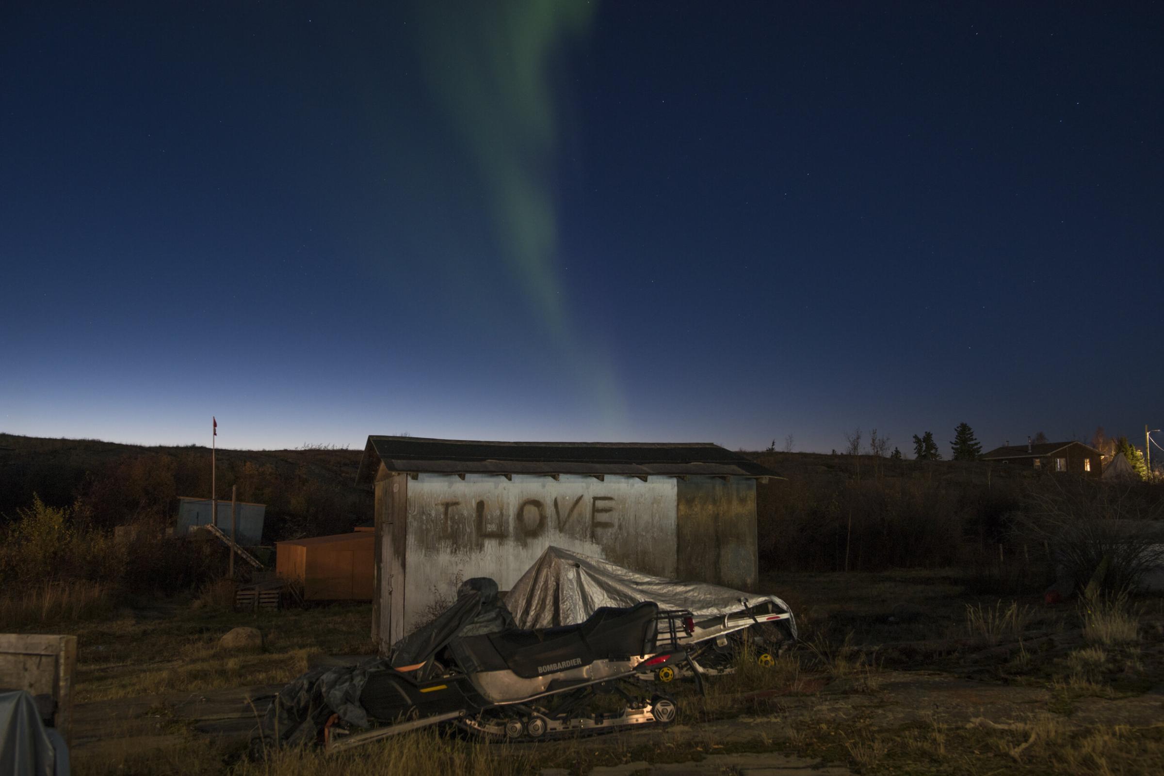 Here Is Where We Shall Stay - The aurora borealis appears over the village of Dettah.
