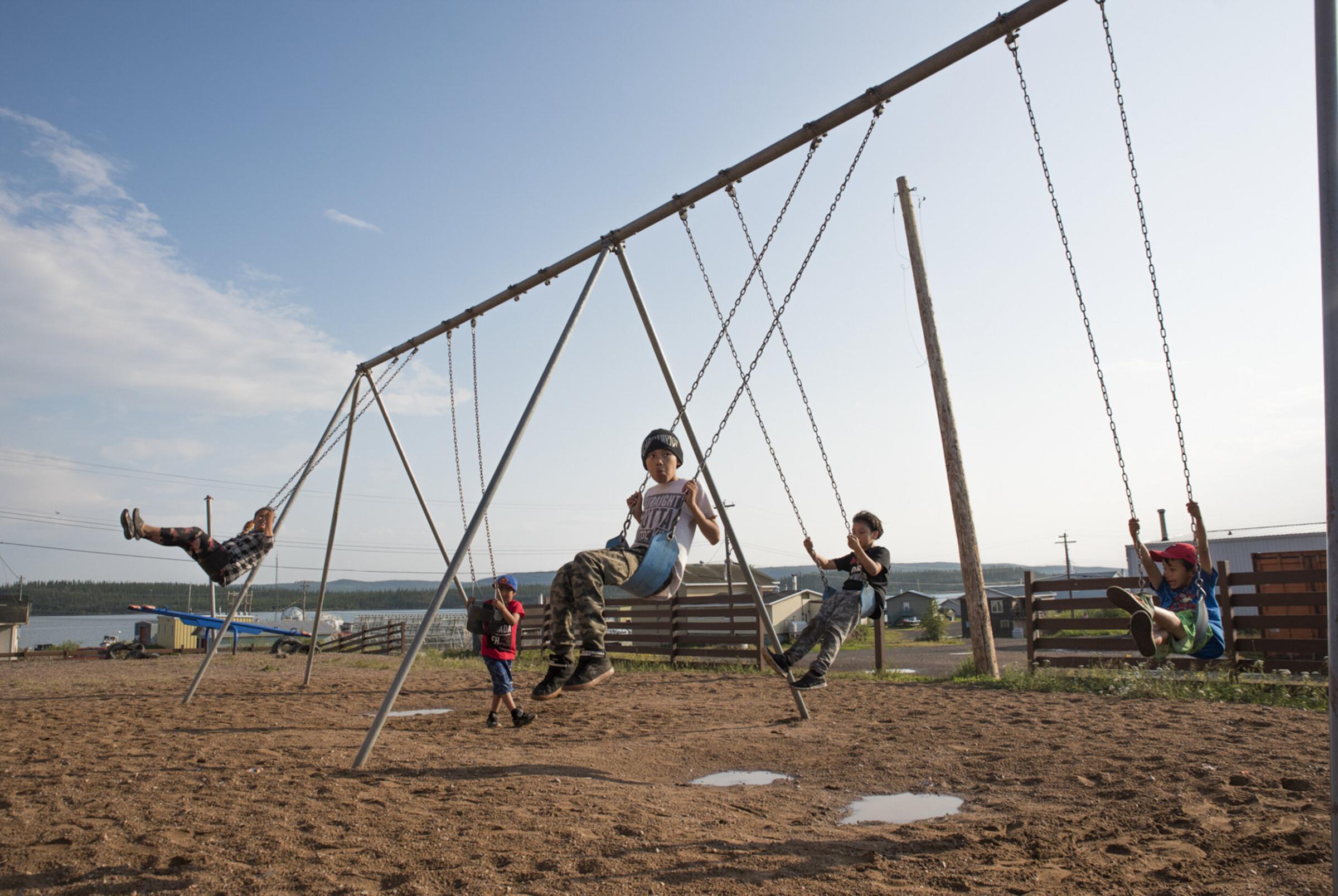 Land of The Ancestors - Kids play on the swings in Łutsel Kʼe.