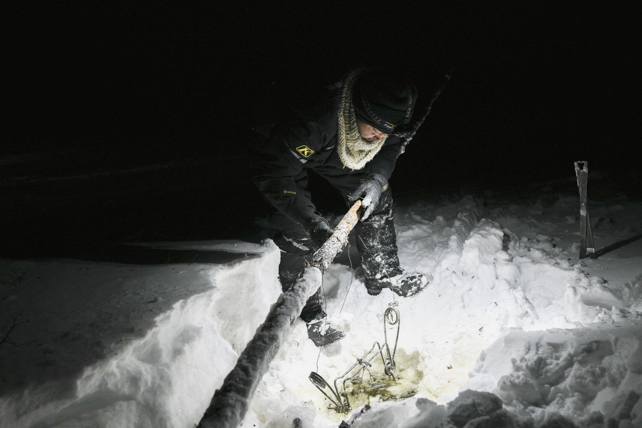The Last Trappers - National Geographic - Nathan Kogiak checks a beaver trap on a lake outside of...