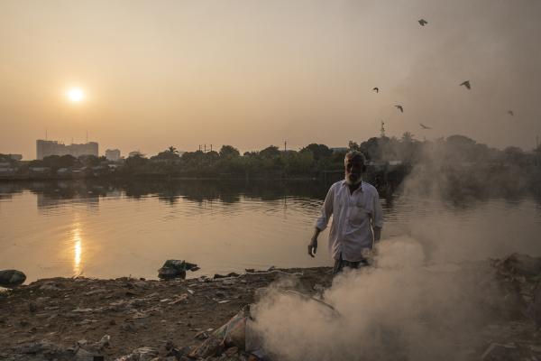 Dangerous job of recycling - A man burns plastic garbage on the shore of Banani Lake, in the Gulshan area, one of the richest...