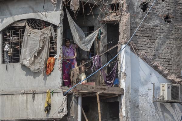 Dangerous job of recycling - A woman and her daughter look from inside their house as their building is being destroyed. In...