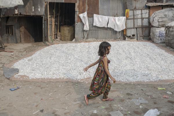 Dangerous job of recycling - A little girl runs and plays in the Baunya-Badh slum in Dhaka, one of the poorest areas of the...