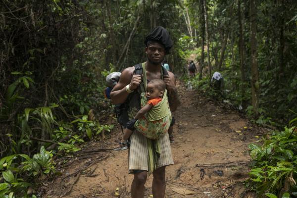 The journey trough Darien Gap - A man of Haitian origin, poses for a portrait. in her arms she carries her little son. Both are...