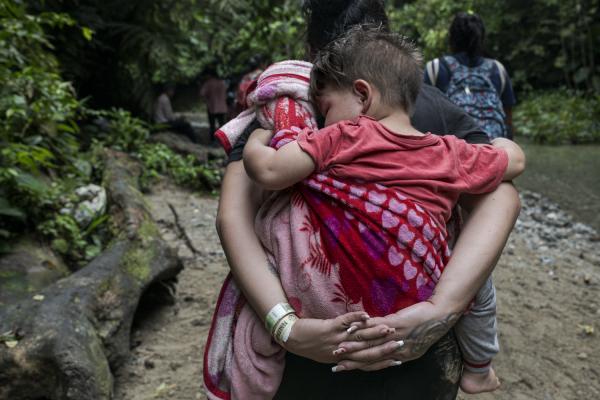 The journey trough Darien Gap - A woman carries her little son on her back. they travel through the Darien jungle with the...