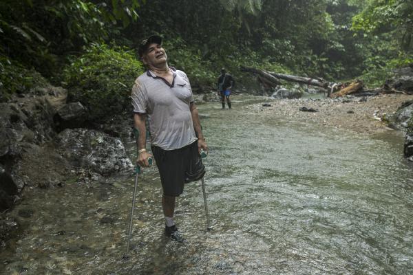 The journey trough Darien Gap - Manuel poses for a portrait on the bed of the Pinlolo river. Under heavy rain and walking with...