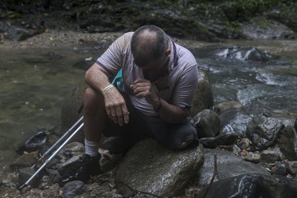 The journey trough Darien Gap - While it rains Manuel takes a break on a rock. Without a leg, the route becomes much more...