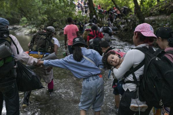 The tortuous journey, the migration through America - A group of people cross the Pinololo River while walking through the Colombian Darien jungle....