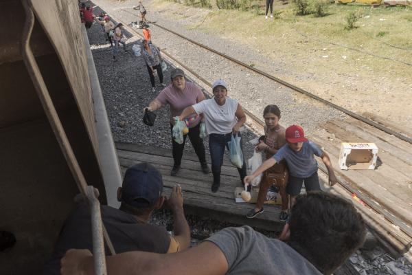The tortuous journey, the migration through America - A group of people offer food and water to migrants traveling in "The Beast" to the...