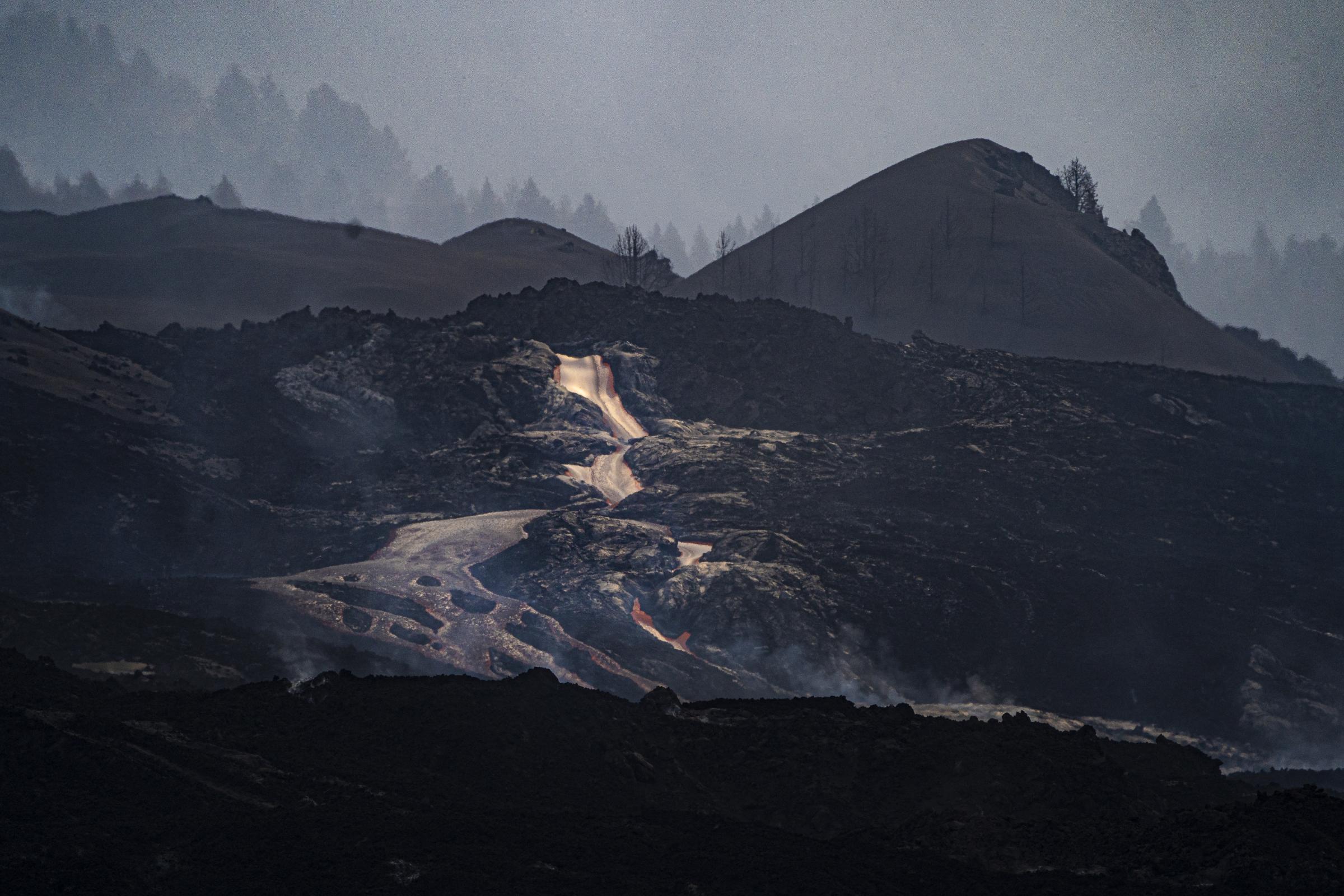 Lava flows down through the lava flow from the summit of the volcano into the sea on the 24th of...