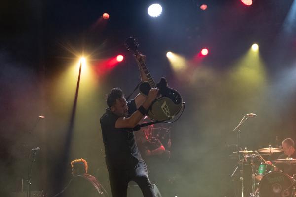 Image from Events - Multi instrumentalist Tim Brennan raising his guitar...