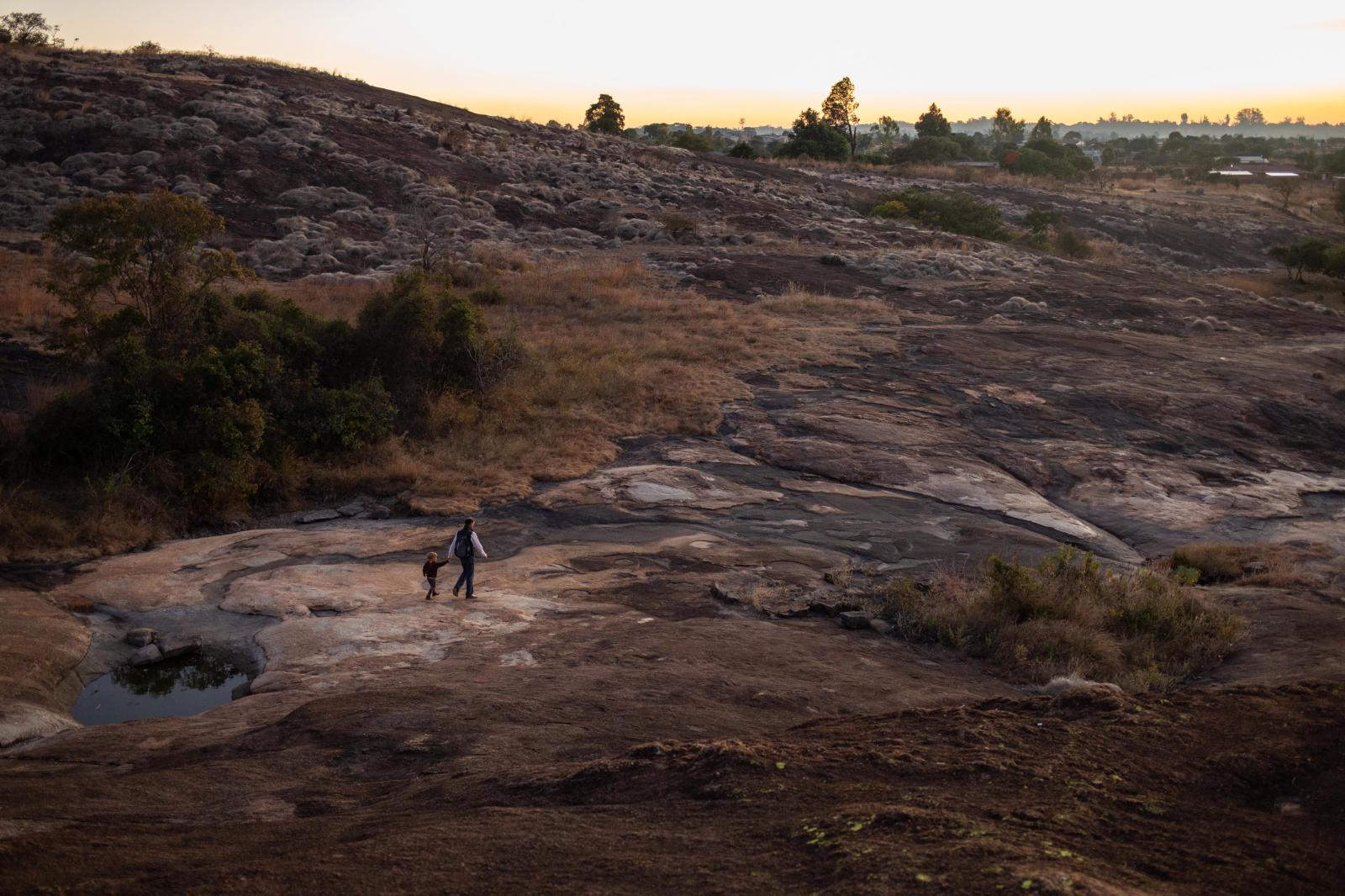 A father and son walk over a la...e Domboshava Caves in Zimbabwe.