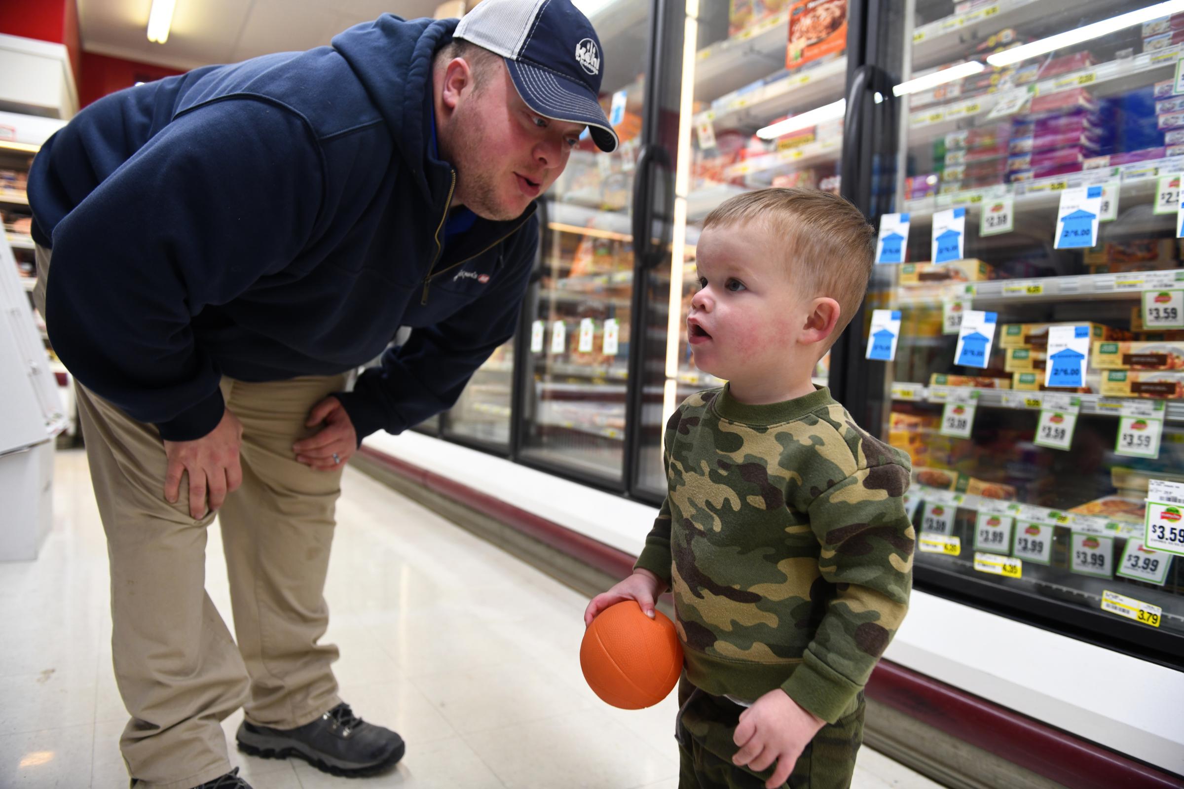 Hickman IGA: Serving community since 1959 - Jordan Branstetter leans down to talk to his son Brooks,...