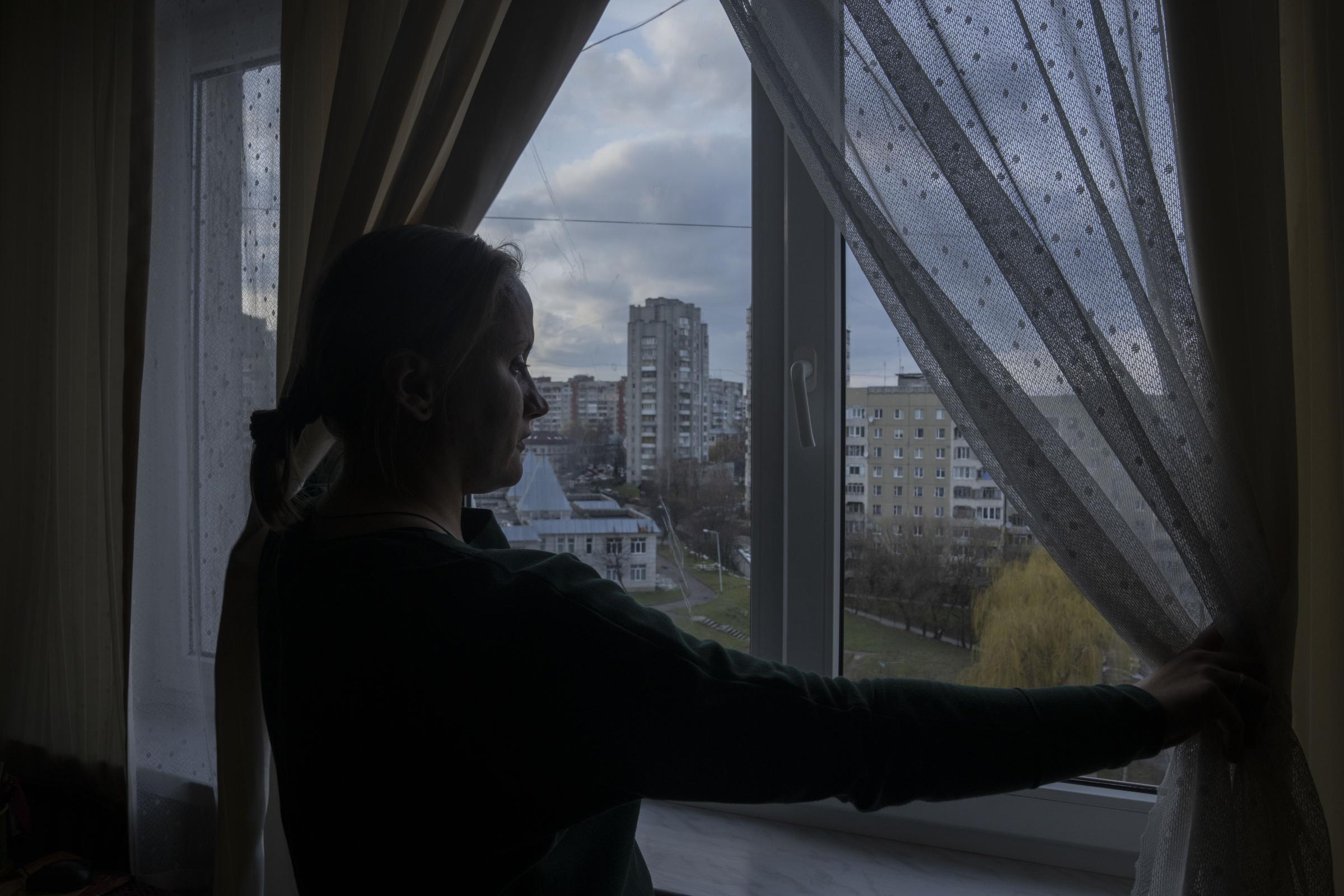 Olha Salivonchuk, head of the local association of apartment owners, looks out of the window in her living area, at her apartment.