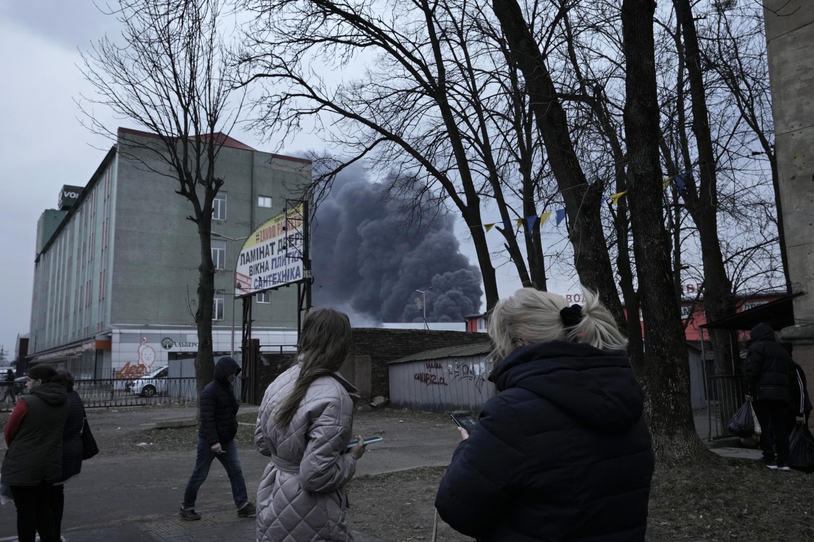  People watch smoke rising behi... following explosions in Lviv. 