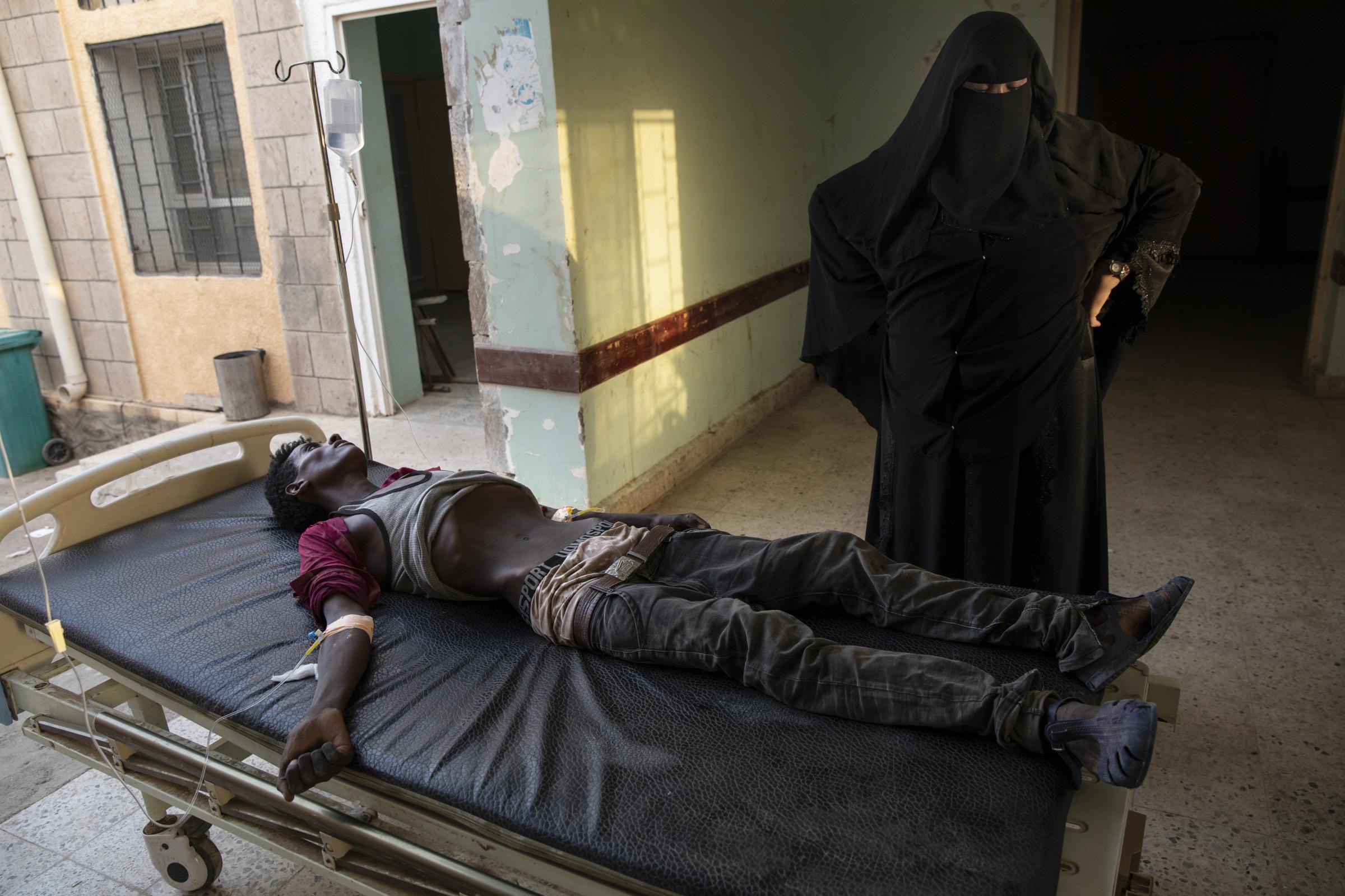  An Ethiopian Tigray migrant who was imprisoned by traffickers for months, lies on a gurney accompanied by a nurse at the Ras al-Ara Hospital in Lahj. He passed away several hours later. 