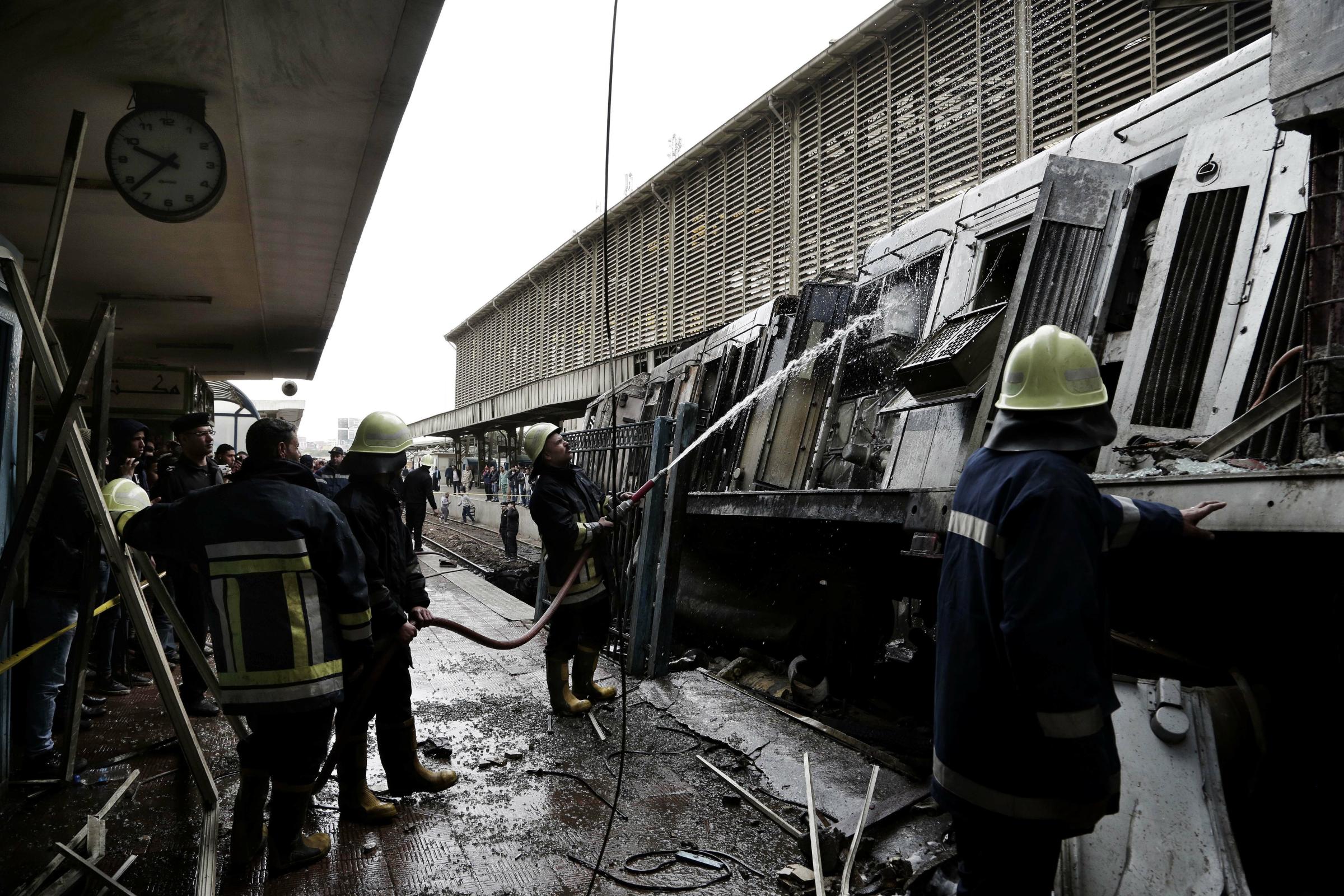  Firefighters hose down a train that was damaged after a crash inside Ramsis train station in Cairo. 
