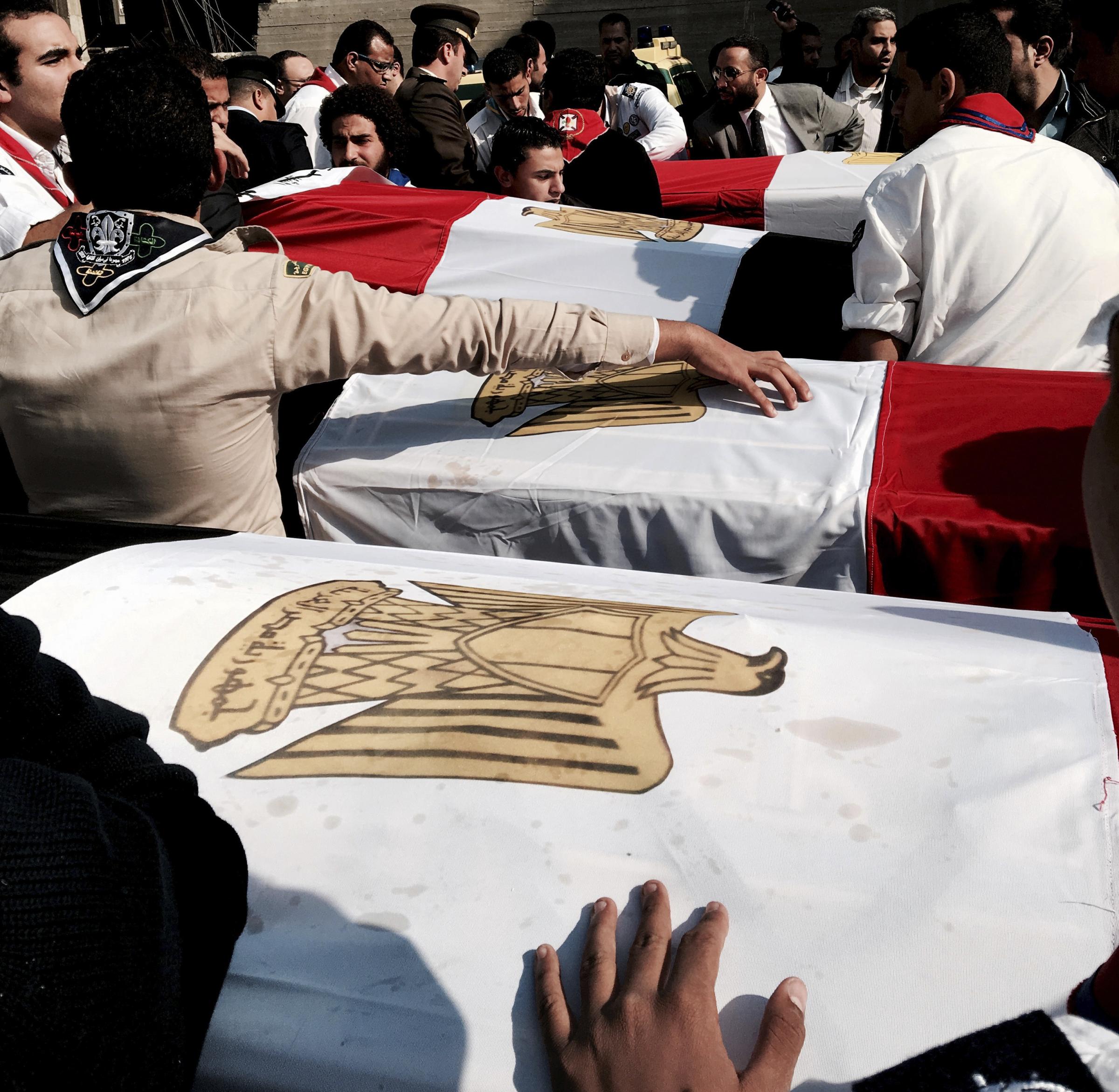  Flags are draped on coffins of victims of a Sunday cathedral bombing after a funeral service, at the Virgin Mary Church, in Cairo. 