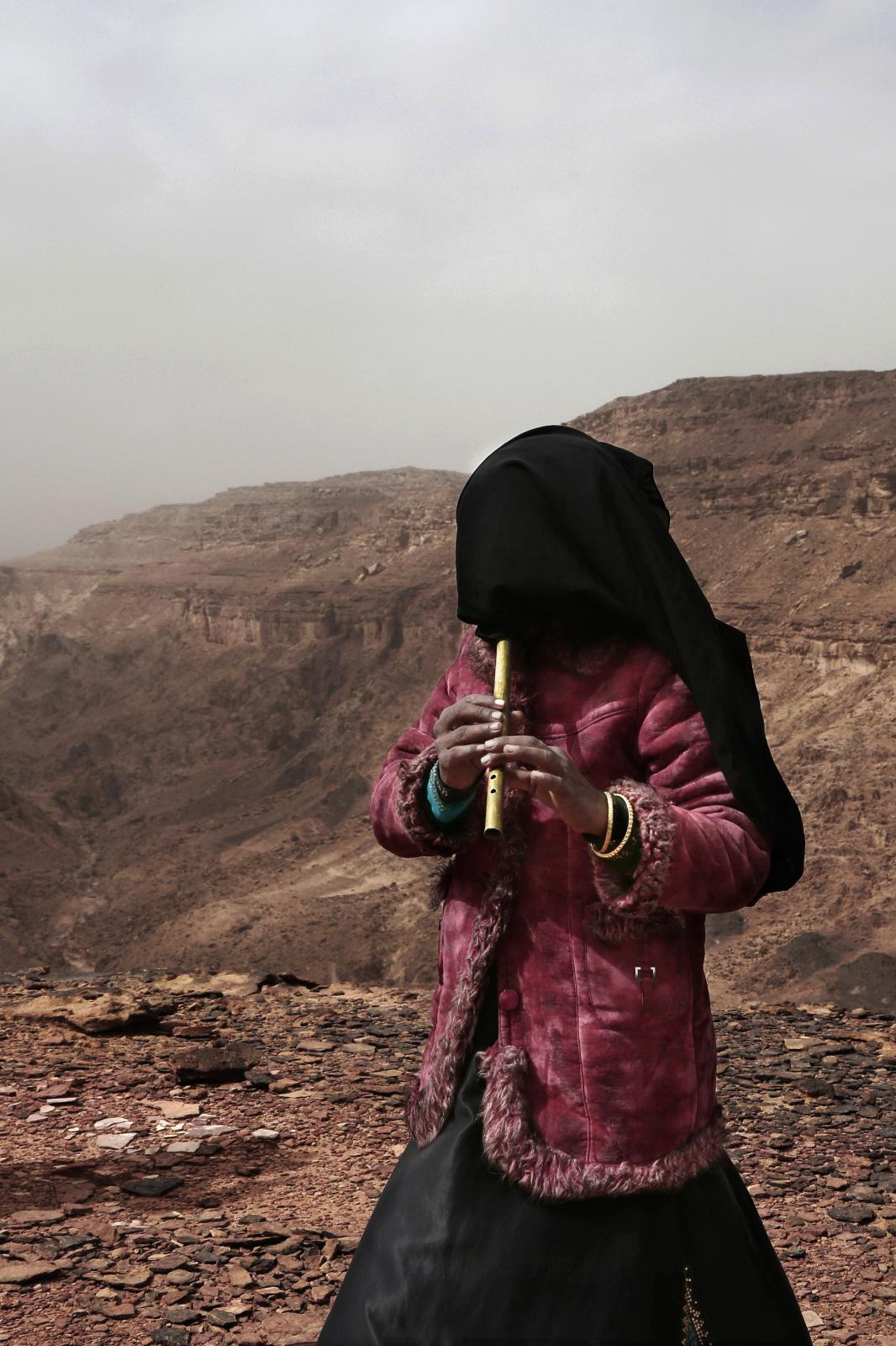 Aicha, from the Hamada tribe and one of the first female guides, plays the flute for tourists on a trek in the mountains.