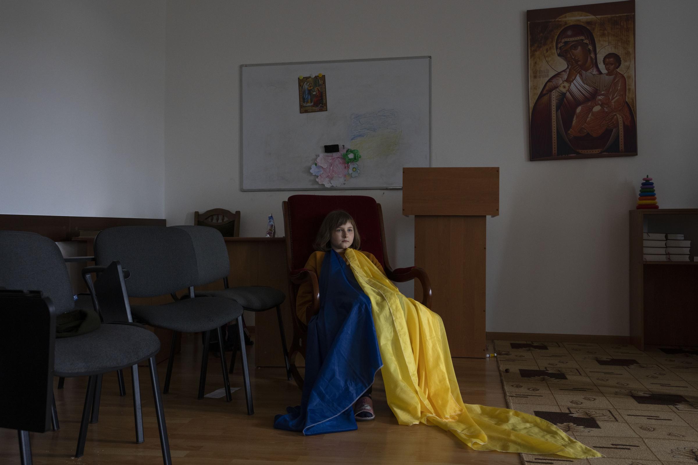 An internally displaced child, wears a make-shift Ukrainian flag.